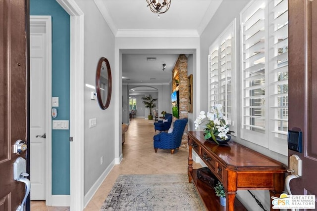 foyer entrance with light tile patterned floors, a notable chandelier, and ornamental molding