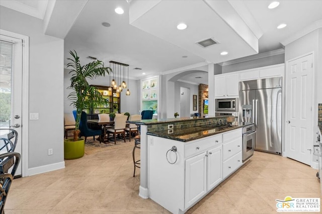 kitchen featuring built in appliances, dark stone countertops, white cabinets, and a kitchen island