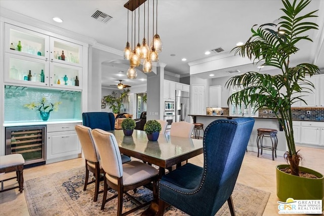 dining space featuring ornamental molding, beverage cooler, ceiling fan, bar area, and light tile patterned flooring