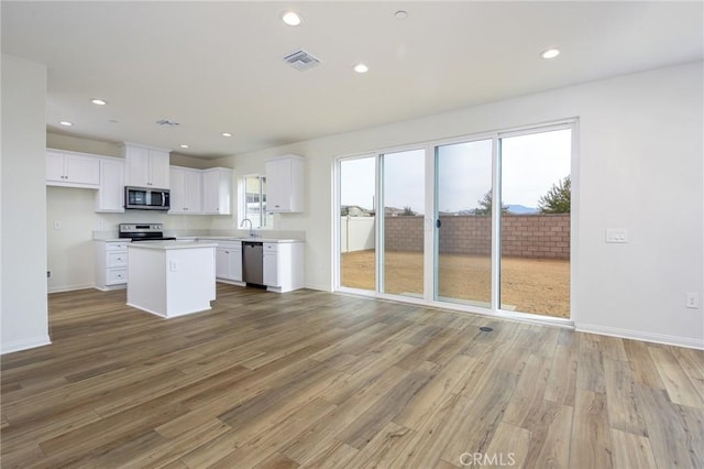 kitchen with a center island, light countertops, visible vents, appliances with stainless steel finishes, and white cabinets