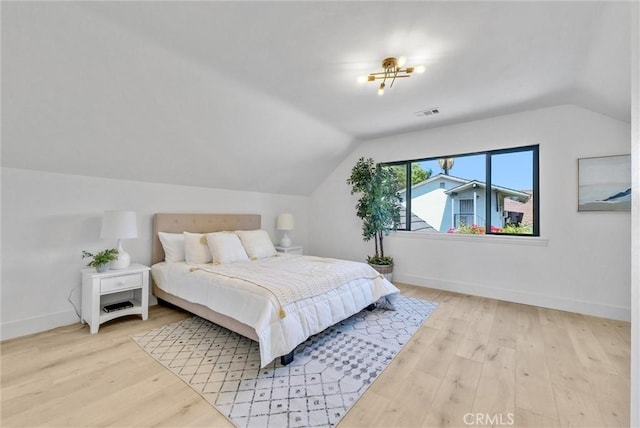 bedroom with light hardwood / wood-style floors and lofted ceiling