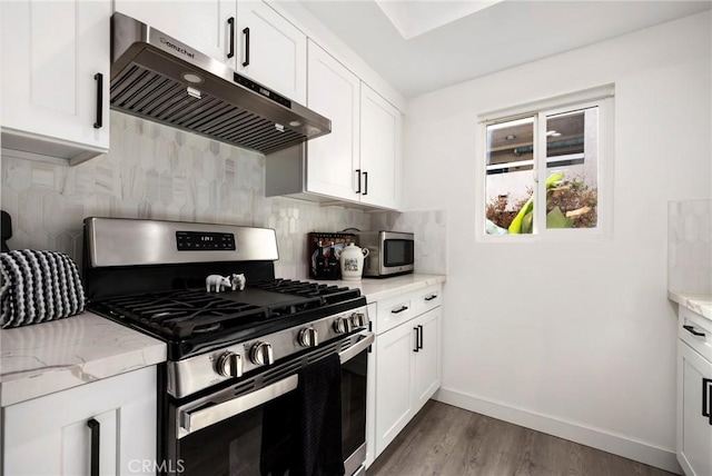 kitchen featuring light stone counters, hardwood / wood-style floors, extractor fan, white cabinets, and appliances with stainless steel finishes