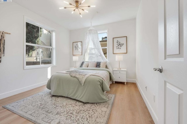 bedroom with multiple windows, wood-type flooring, and an inviting chandelier