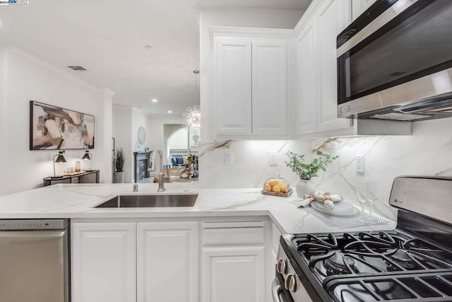 kitchen featuring stainless steel appliances, white cabinetry, tasteful backsplash, and sink