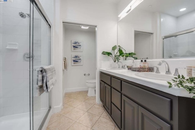 bathroom featuring tile patterned floors, vanity, toilet, and a shower with shower door