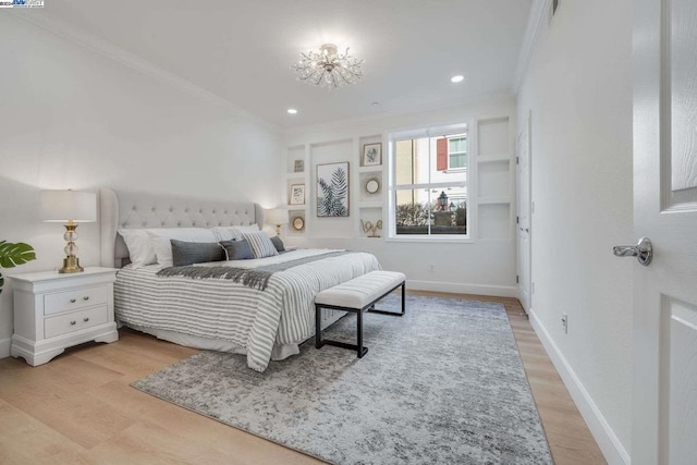 bedroom with crown molding, light hardwood / wood-style flooring, and an inviting chandelier