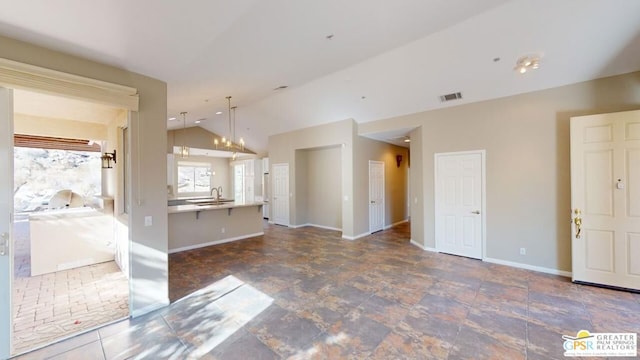 kitchen with vaulted ceiling, sink, hanging light fixtures, and a notable chandelier