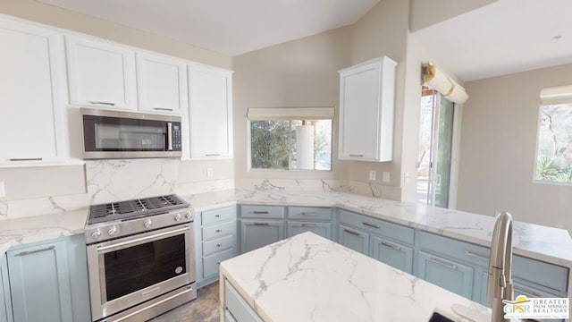 kitchen featuring white cabinetry, tasteful backsplash, light stone countertops, and appliances with stainless steel finishes