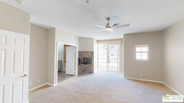 unfurnished living room with ceiling fan, light colored carpet, and a tile fireplace