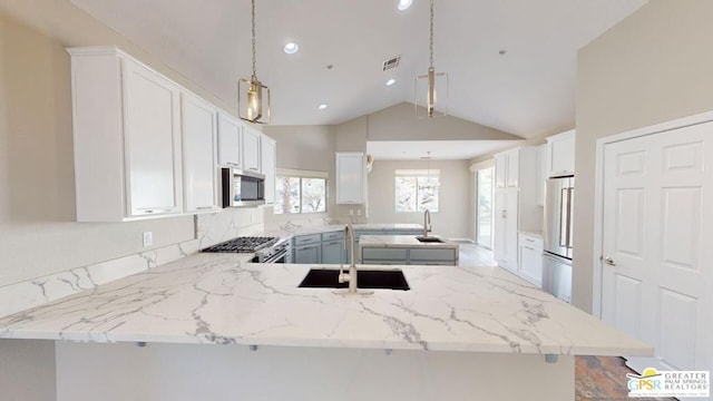 kitchen featuring decorative light fixtures, sink, white cabinets, premium appliances, and kitchen peninsula