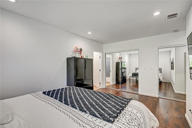 bedroom with two closets and dark wood-type flooring