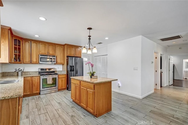 kitchen featuring a center island, an inviting chandelier, hanging light fixtures, light hardwood / wood-style flooring, and appliances with stainless steel finishes