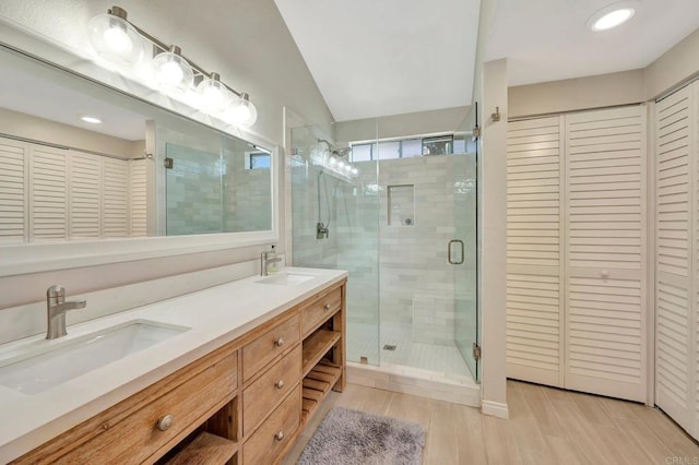 bathroom featuring hardwood / wood-style flooring, vanity, walk in shower, and vaulted ceiling