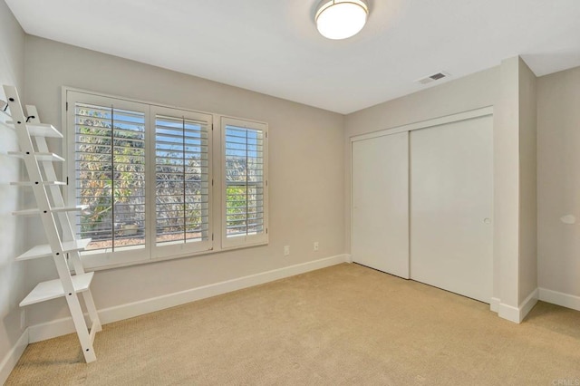 unfurnished bedroom featuring light carpet and a closet