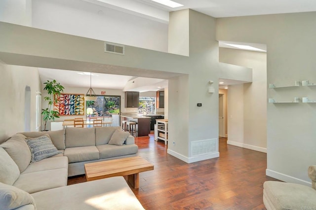 living room featuring dark wood-type flooring and high vaulted ceiling