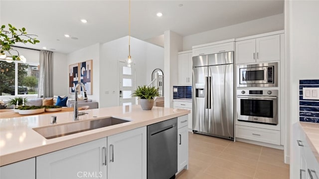 kitchen featuring sink, hanging light fixtures, light tile patterned floors, built in appliances, and white cabinets