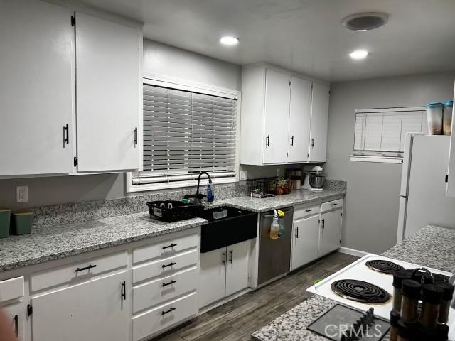 kitchen featuring white refrigerator, stainless steel dishwasher, white cabinetry, and sink