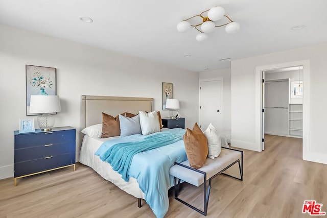 bedroom with a closet, a spacious closet, and light hardwood / wood-style flooring