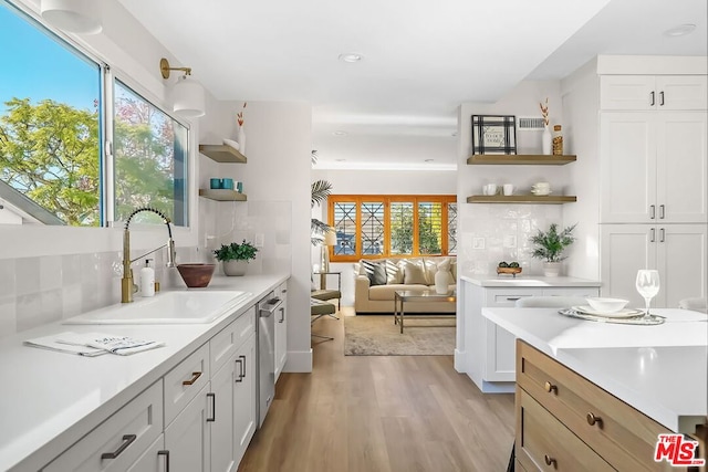 kitchen featuring white cabinetry, sink, backsplash, and light hardwood / wood-style floors