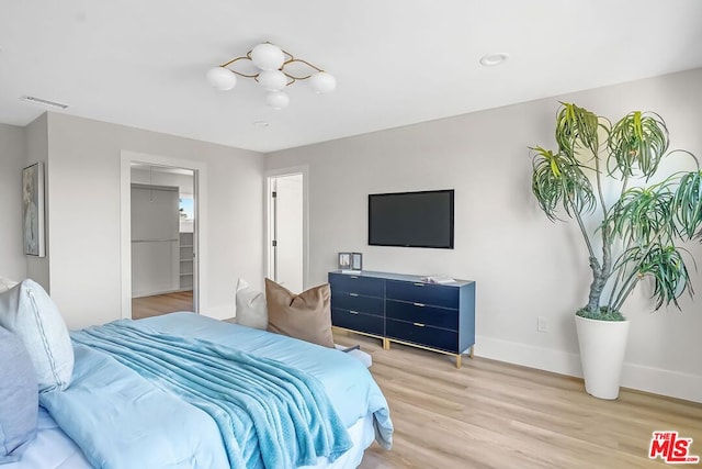 bedroom with wood-type flooring, a walk in closet, and a closet