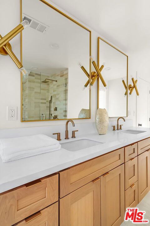 bathroom featuring a shower with door and vanity