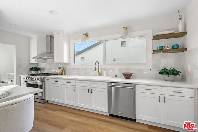 kitchen featuring white cabinetry, sink, backsplash, stainless steel appliances, and wall chimney exhaust hood