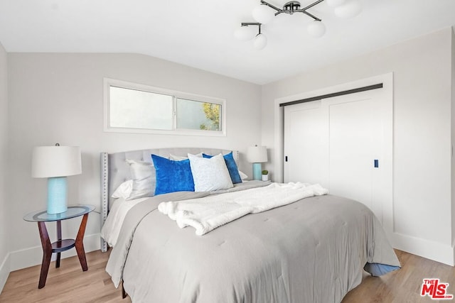 bedroom with vaulted ceiling, light hardwood / wood-style floors, and a closet