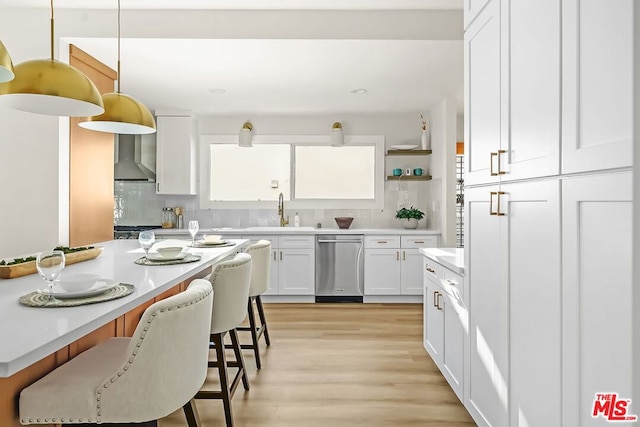 kitchen with sink, a breakfast bar area, hanging light fixtures, white cabinets, and stainless steel dishwasher