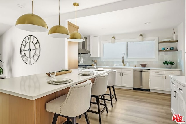 kitchen featuring sink, white cabinets, decorative light fixtures, stainless steel dishwasher, and wall chimney exhaust hood