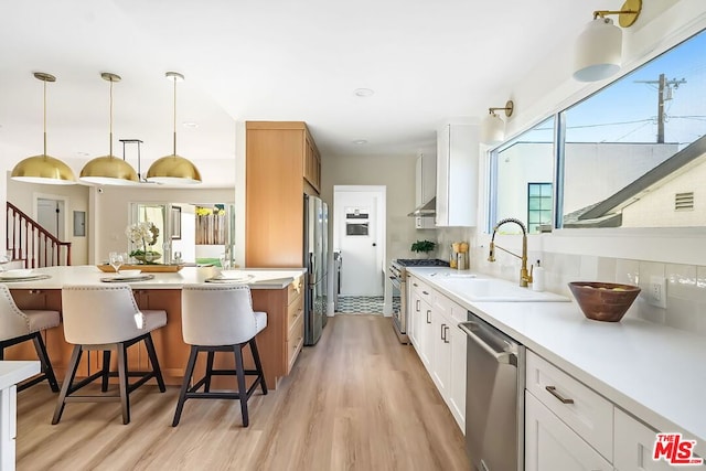 kitchen featuring hanging light fixtures, white cabinetry, appliances with stainless steel finishes, and sink