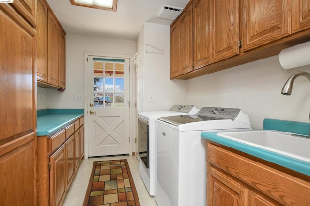 clothes washing area with washer and clothes dryer, light tile patterned flooring, cabinets, and sink