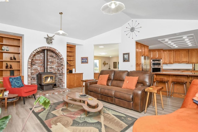 living room with built in shelves, light wood-type flooring, a wood stove, and vaulted ceiling