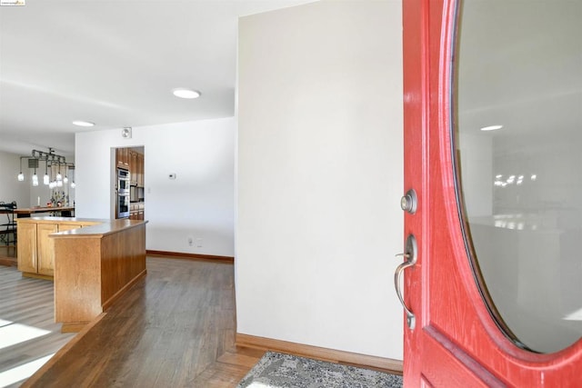 kitchen with double oven, hardwood / wood-style floors, and light brown cabinets