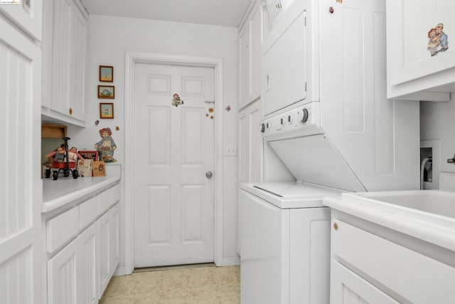 laundry room featuring stacked washer / drying machine and cabinets