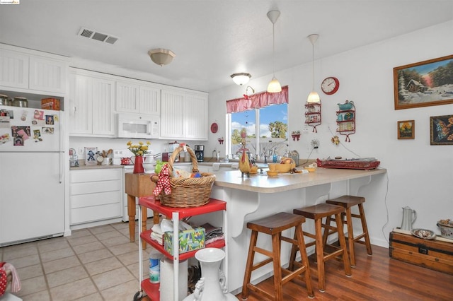 kitchen with white cabinets, hanging light fixtures, and white appliances