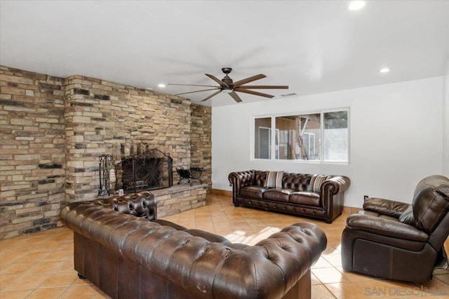 living room with a stone fireplace, ceiling fan, and light tile patterned floors