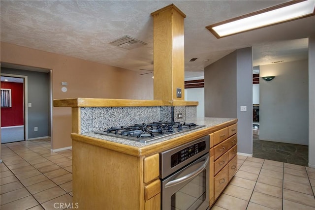 kitchen featuring ceiling fan, light tile patterned floors, appliances with stainless steel finishes, and tasteful backsplash