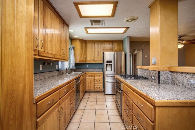 kitchen with sink, light tile patterned floors, ceiling fan, and stainless steel appliances