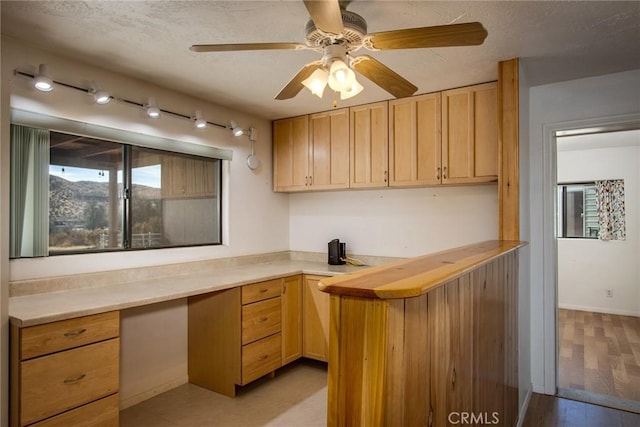 kitchen with light brown cabinetry, ceiling fan, light hardwood / wood-style floors, butcher block counters, and built in desk