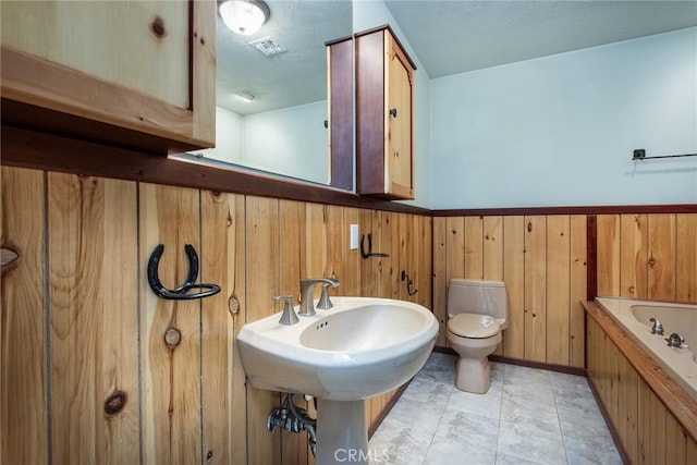 bathroom featuring a bathtub, wooden walls, and toilet