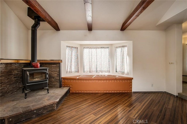 unfurnished living room featuring beamed ceiling, a wood stove, and dark hardwood / wood-style flooring