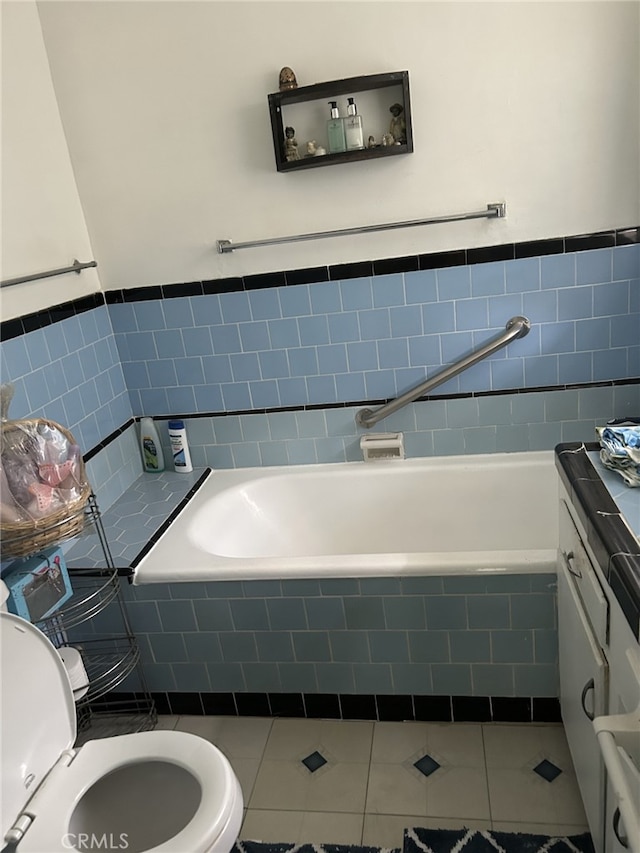 bathroom featuring tile patterned flooring, vanity, a relaxing tiled tub, and toilet