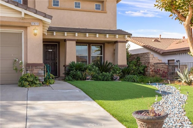 view of exterior entry with a lawn and a garage