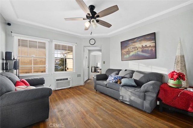 living room with ceiling fan, wood-type flooring, an AC wall unit, and a raised ceiling