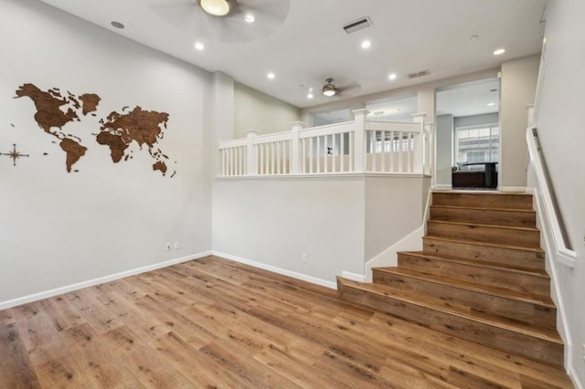 stairway with hardwood / wood-style flooring and ceiling fan