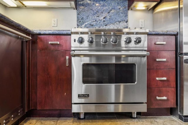 kitchen with backsplash, high end stainless steel range oven, and dark stone counters