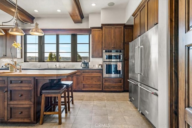 kitchen with backsplash, stainless steel appliances, beam ceiling, pendant lighting, and a breakfast bar area