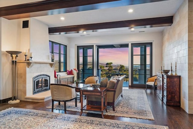 dining space featuring a tiled fireplace, beamed ceiling, and dark hardwood / wood-style floors