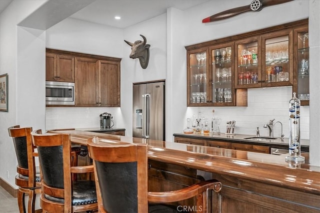 bar featuring stainless steel appliances, tasteful backsplash, and sink