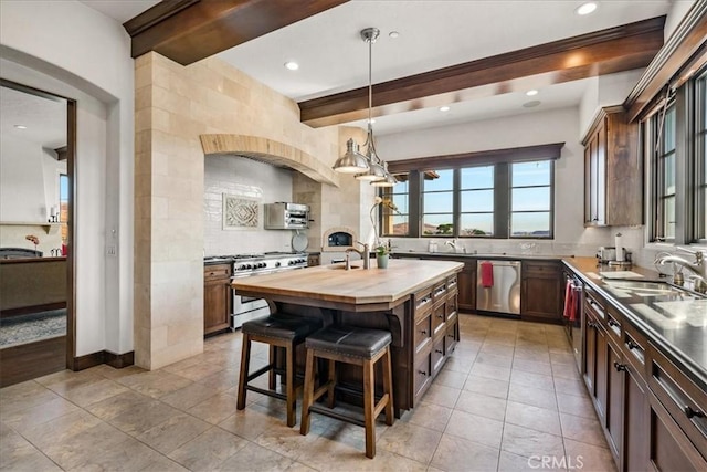 kitchen featuring sink, a center island, beamed ceiling, butcher block countertops, and appliances with stainless steel finishes